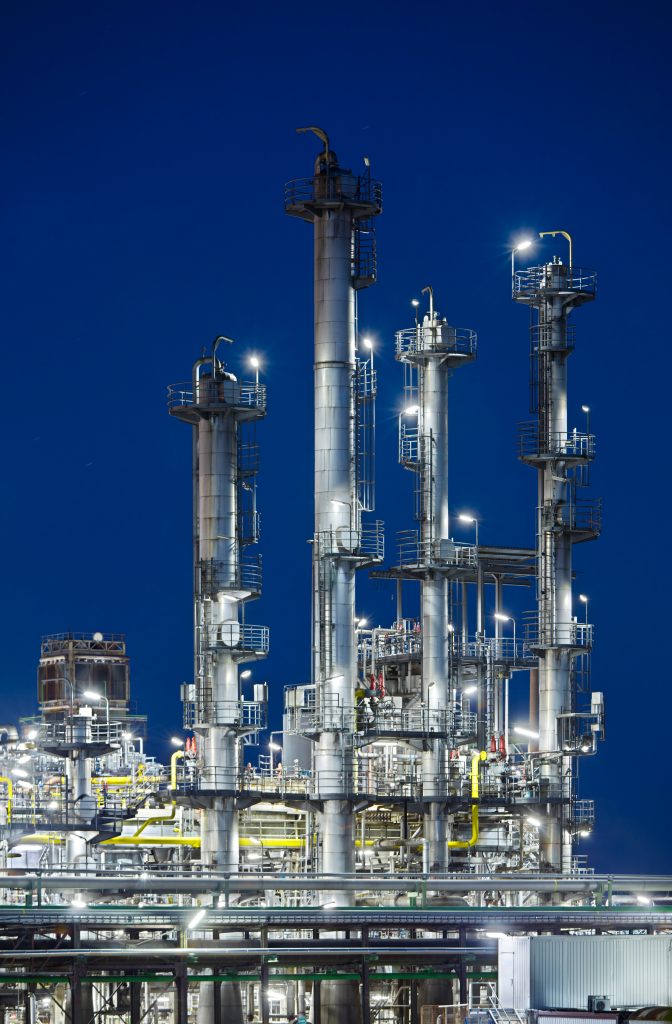 Vertical Shot Of An Oil Refinery With Night Blue Sky.