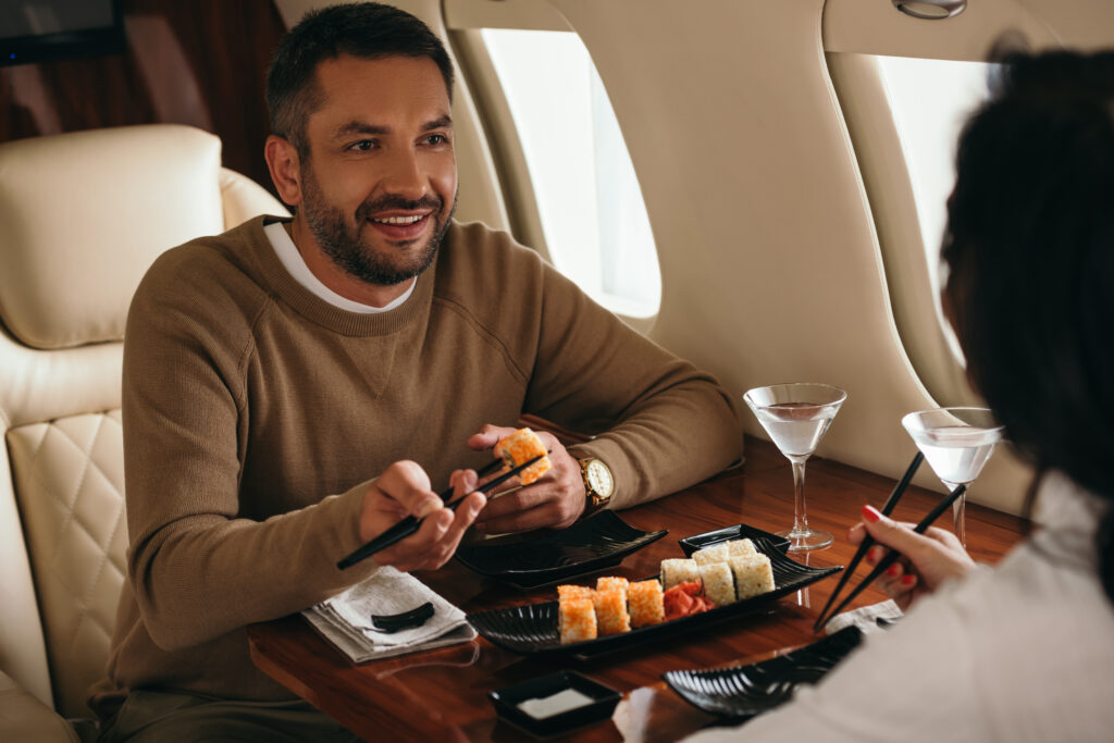 Executive eating sushi and discussing business inside a private jet charter flight